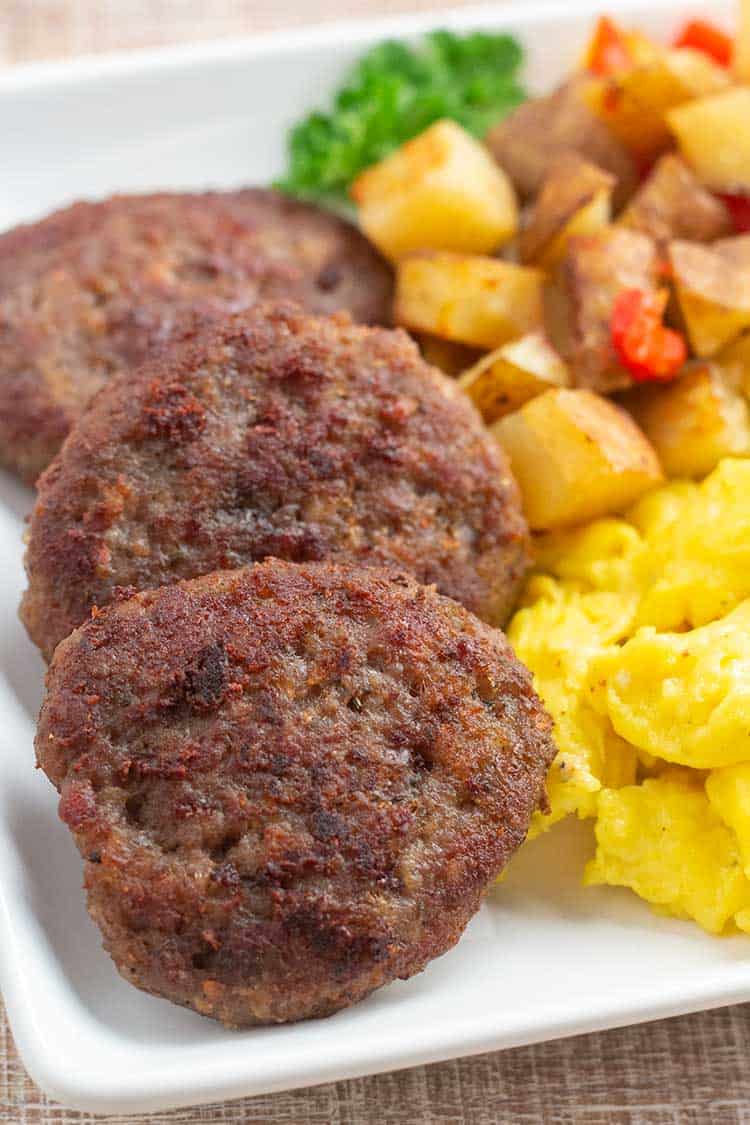 Homemade Italian Sausage patties on plate with eggs and potatoes.