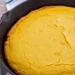 Cornbread in cast iron skillet with linen in background.