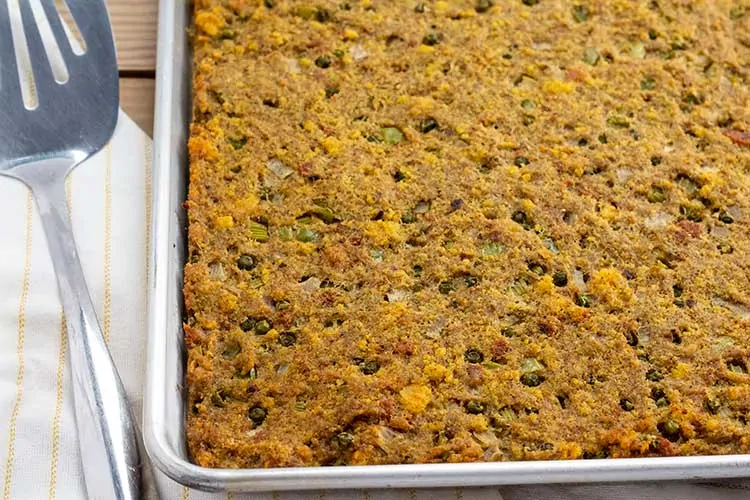 Southern Cornbread Dressing in sheet pan with spatula.