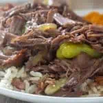 Mississippi pot roast served over rice on a white plate.