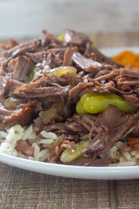 Mississippi pot roast served over rice on a white plate.