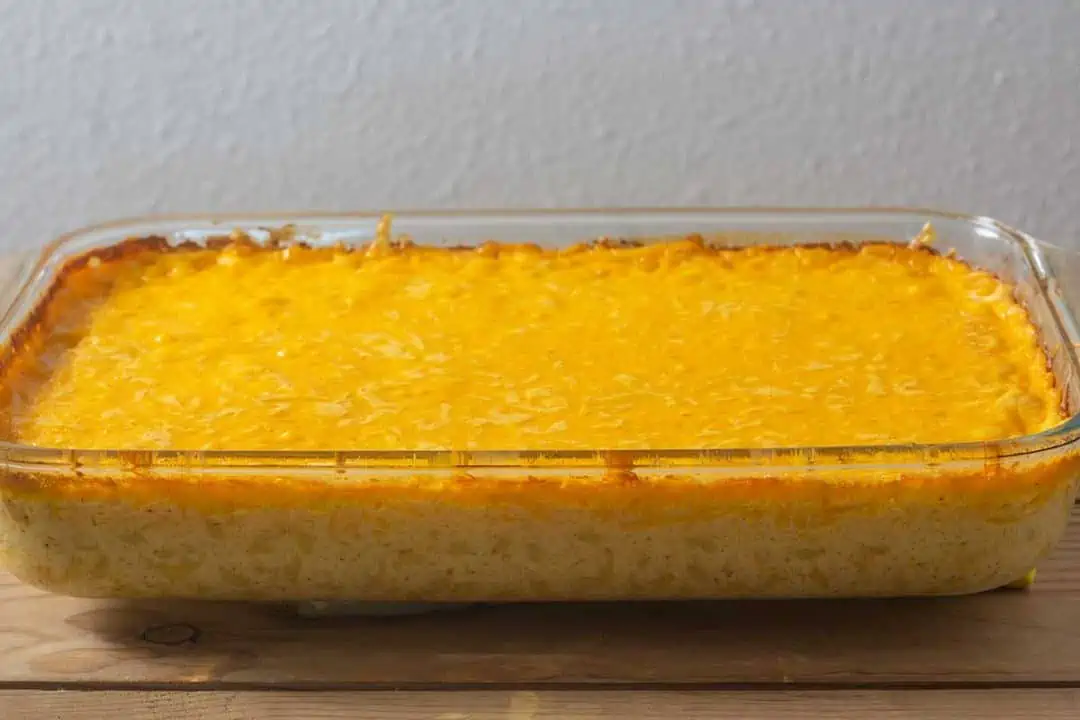 Full casserole dish of baked mac and cheese on wood table.