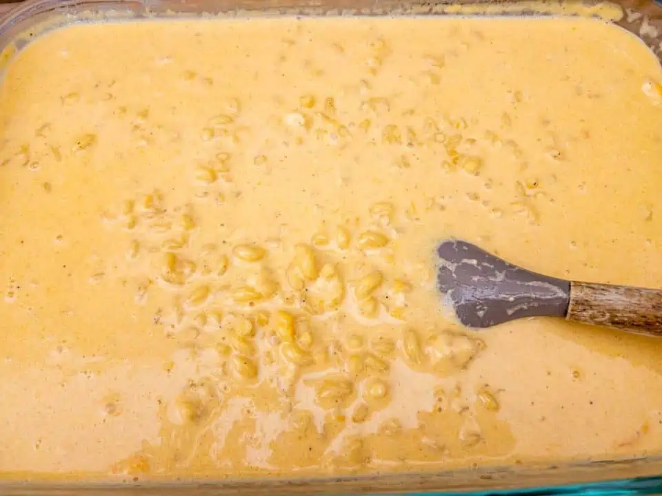 partially cooked mac and cheese being stirred with spatula.