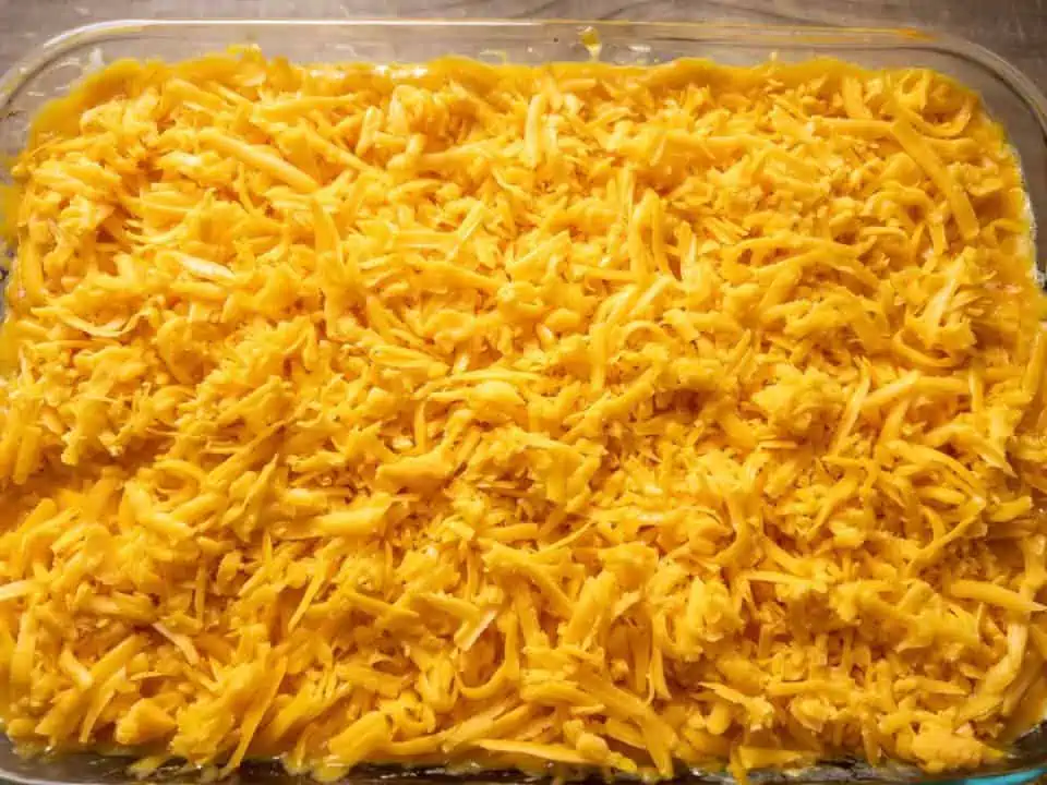 casserole dish topped with a layer of shredded cheddar cheese.