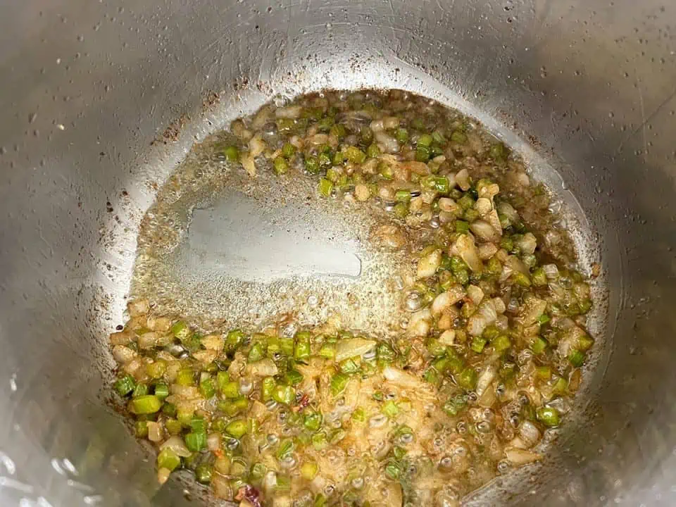 bottom of Instant Pot with diced onions and peppers sautéing in bacon fat