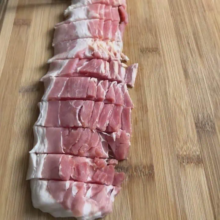 Four slices of bacon cut crosswise into ½-inch pieces on wood cutting board.
