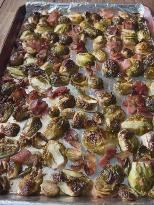 Maple bacon Brussels sprouts on a baking sheet lined with foil.