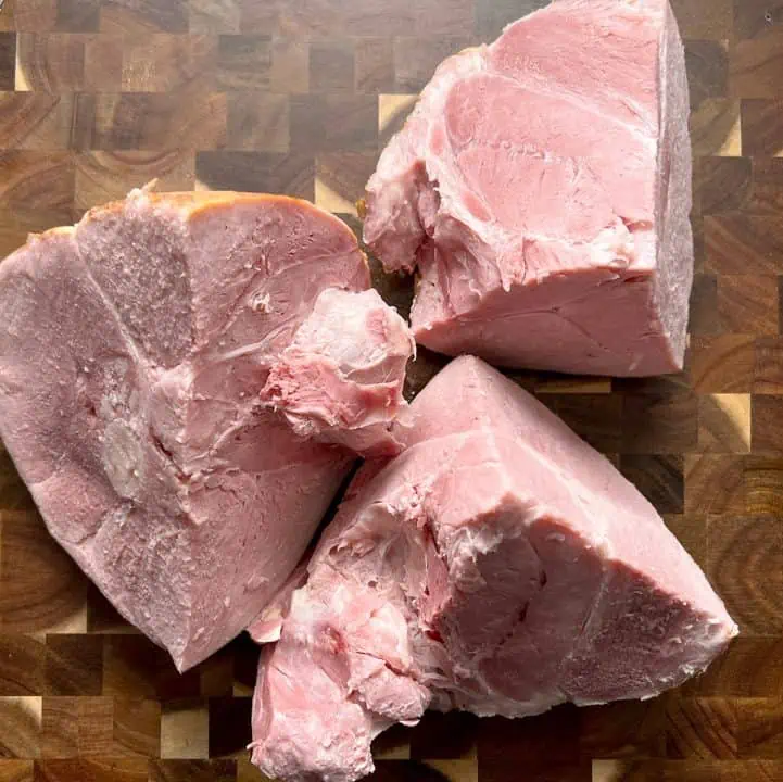 Ham cut into 3 large chunks on cutting board.