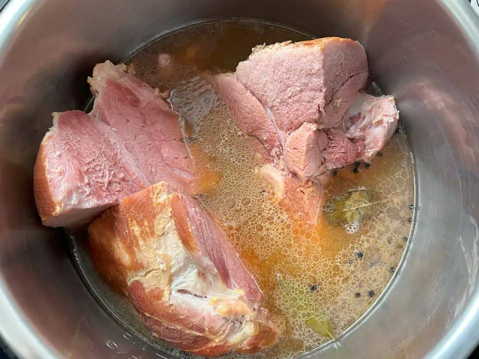Cooked ham in pot with broth.