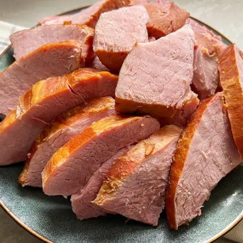 Sliced ham pieces on a plate with gray background.