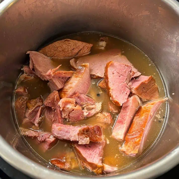 Sliced ham pieces in an Instant Pot with broth.