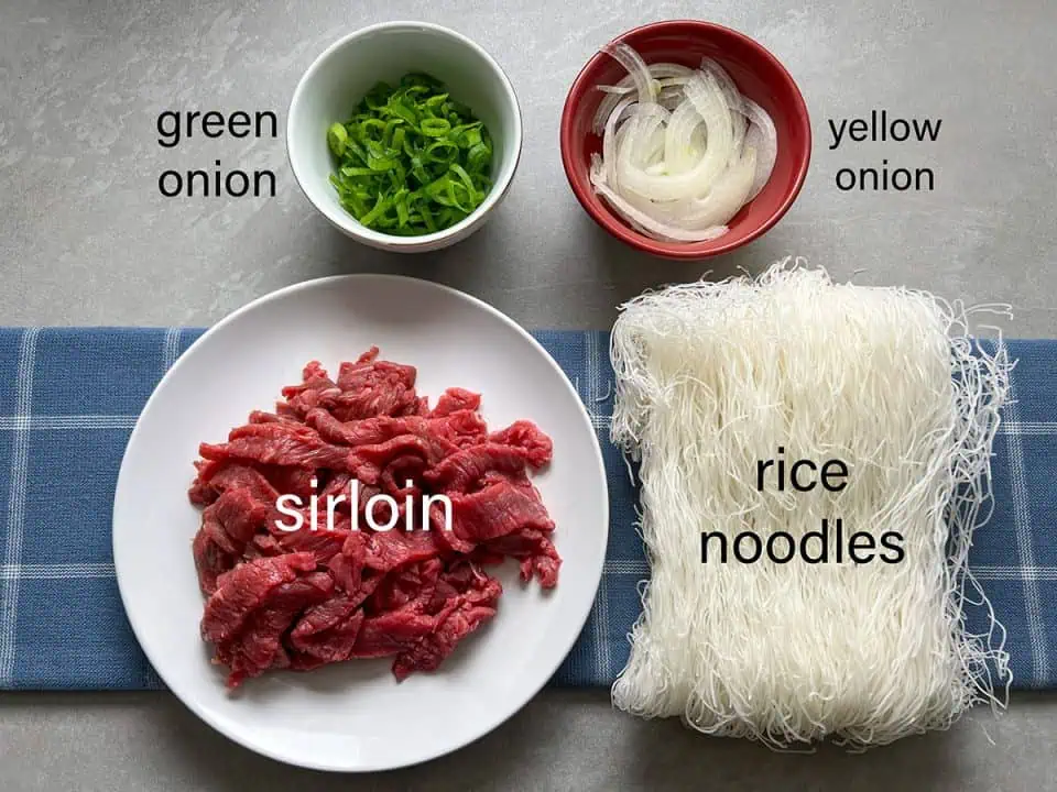 Ingredients for Instant Pot Pho on blue linen with gray background.