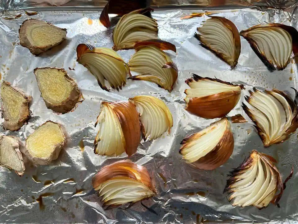 Roasted onions and ginger on a baking tray.