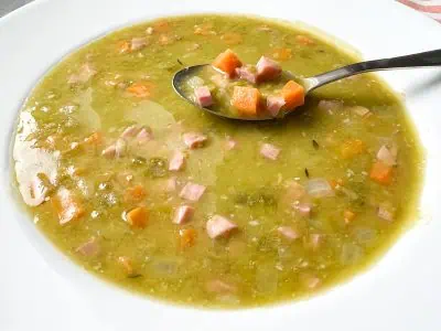 Split pea soup in a white bowl with spoon.