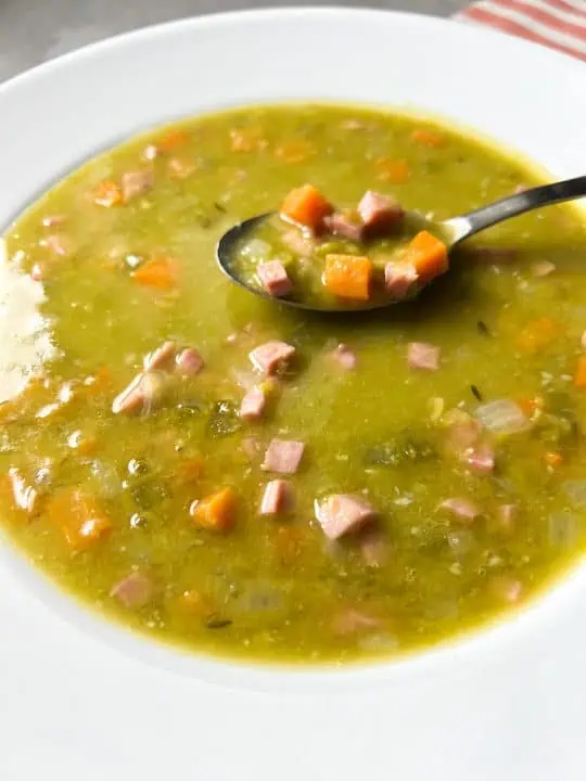 Split pea soup in a white bowl with spoon.