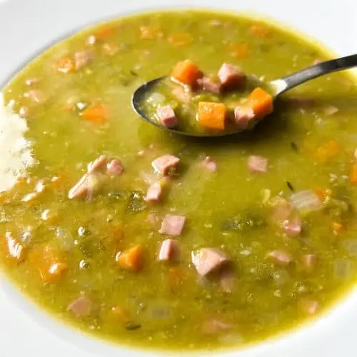 Split pea soup in a white bowl with spoon.