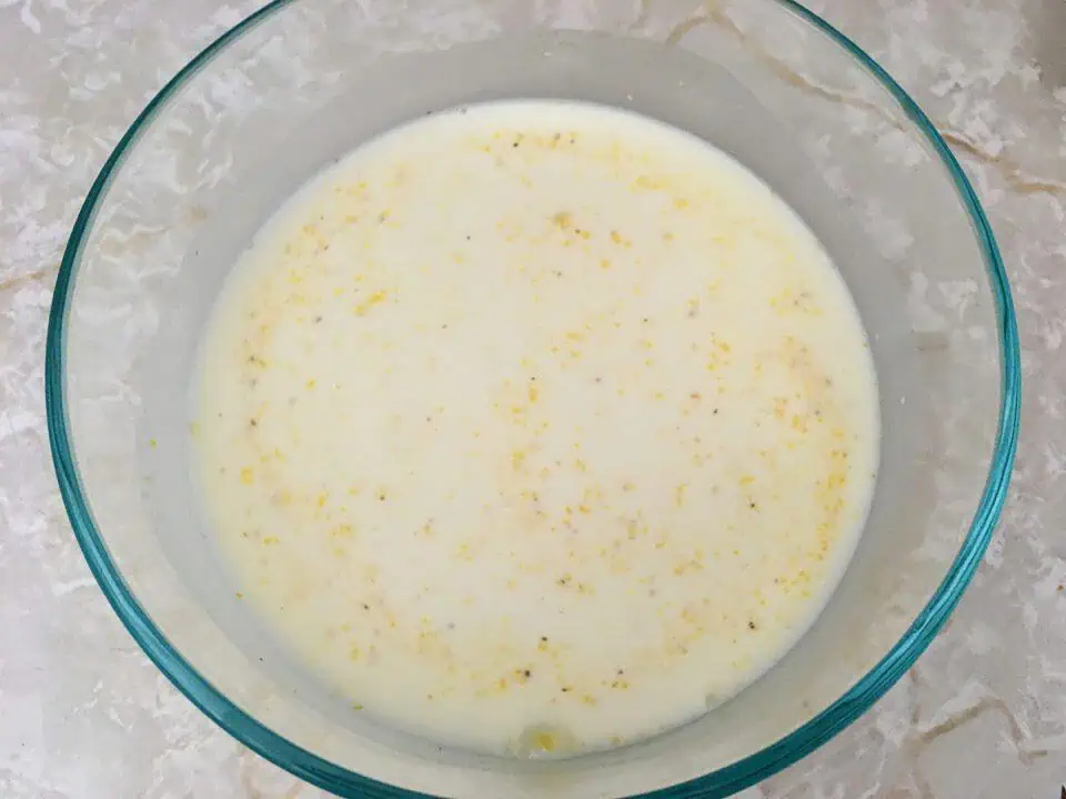 Uncooked grits and milk in glass dish.