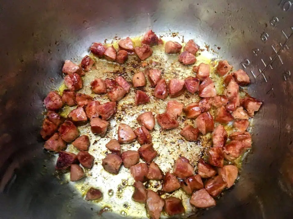 Diced andouille sausage browning in pot.