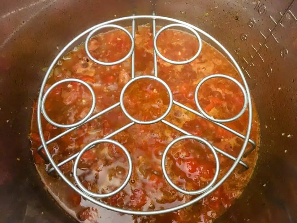 Tomato and white wine sauce in pot with a trivet on top.