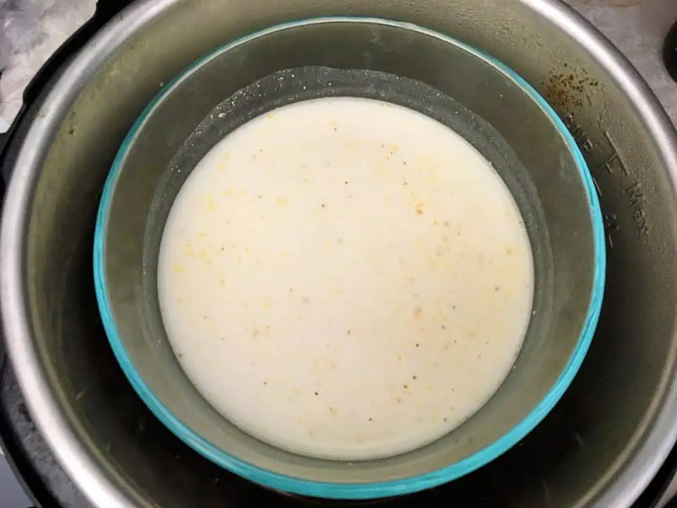 Glass bowl of uncooked grits with milk in Instant Pot.