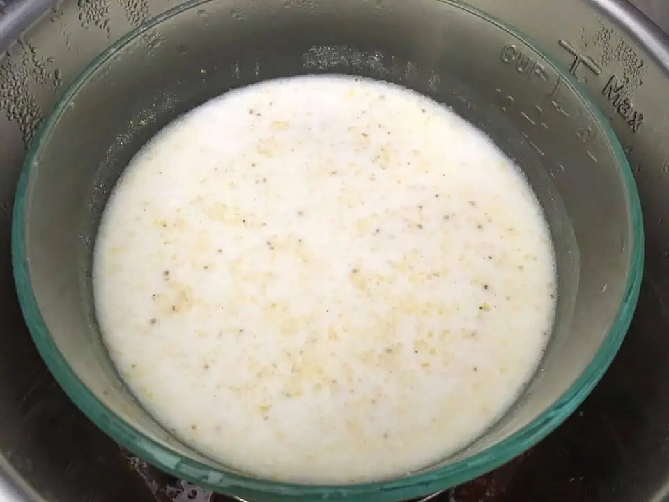 Glass bowl of cooked grits with milk in Instant Pot.