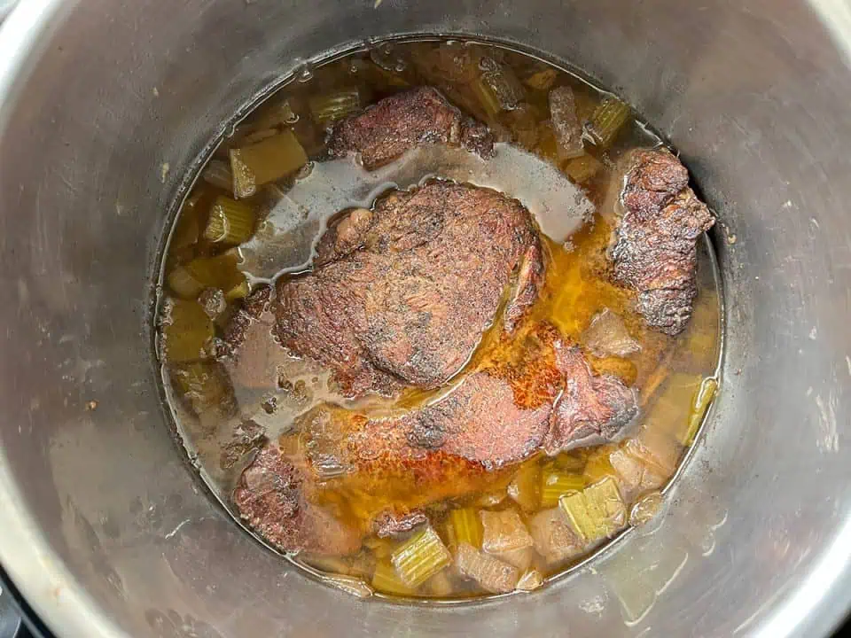 Cooked whole chuck roast in broth with veggies.