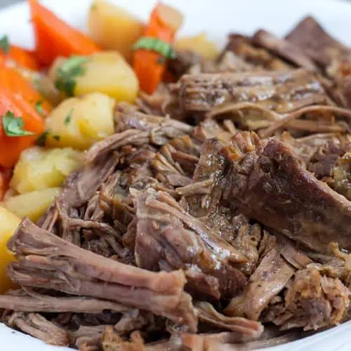 Pressure Cooker Pot Roast in white bowl with potatoes and carrots.