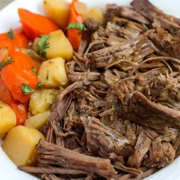 Pressure Cooker Pot Roast in white bowl with potatoes and carrots.