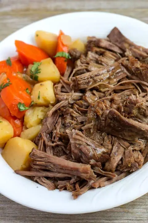 Pressure Cooker Pot Roast in white bowl with potatoes and carrots.
