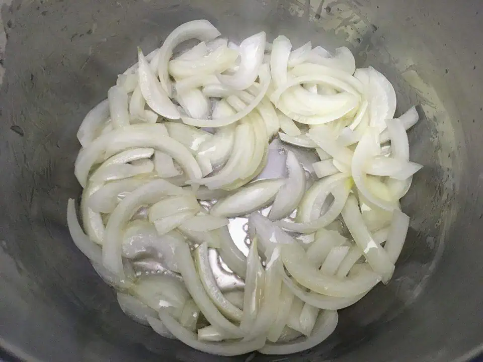 Sliced onions cooking in oil in Instant Pot.