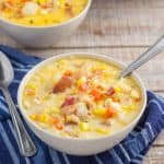 Two bowls of Instant Pot corn chowder on wood palette with blue napkin.