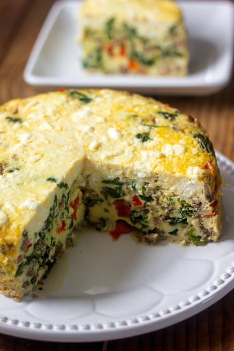 Instant Pot frittata on white plate with large slice cut out on separate plate in the background.