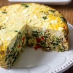 Instant Pot frittata on white plate with large slice cut out.