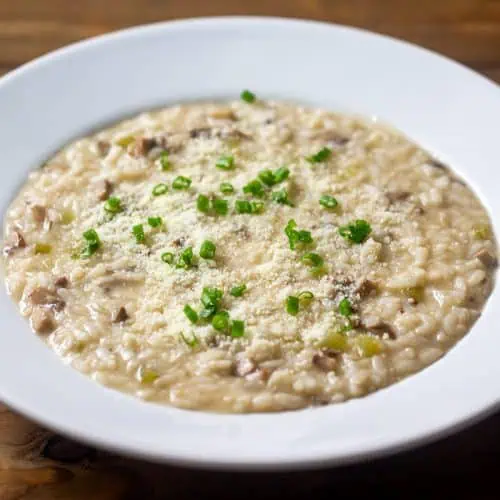 Instant Pot mushroom risotto in white bowl on wood table.