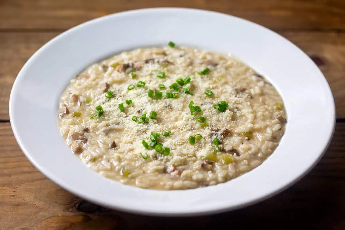 Instant Pot mushroom risotto in white bowl on wood table.