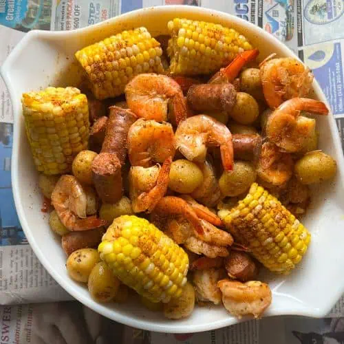 Instant Pot shrimp boil in large white bowl with newspaper background.