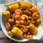 Instant Pot shrimp boil in large white bowl with newspaper background.