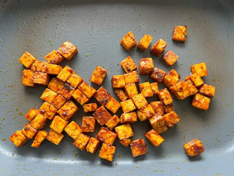 Small cubes of tofu caramelizing in electric skillet.