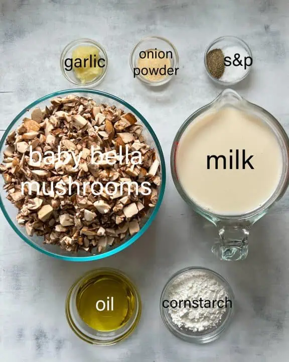 Ingredients for cream of mushroom soup on a white marble background.