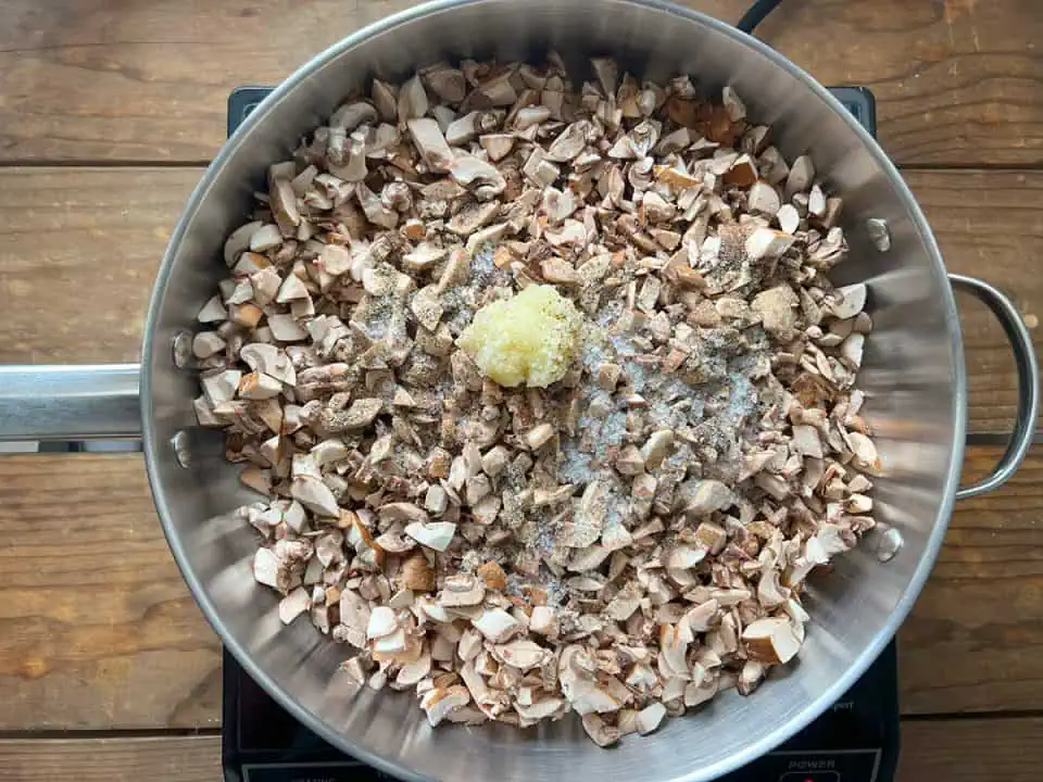 Diced mushrooms in pan with salt, pepper, and garlic