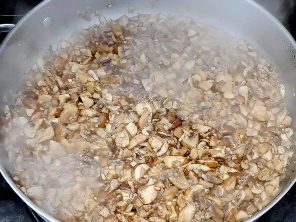 Mushrooms sautéing in pan.