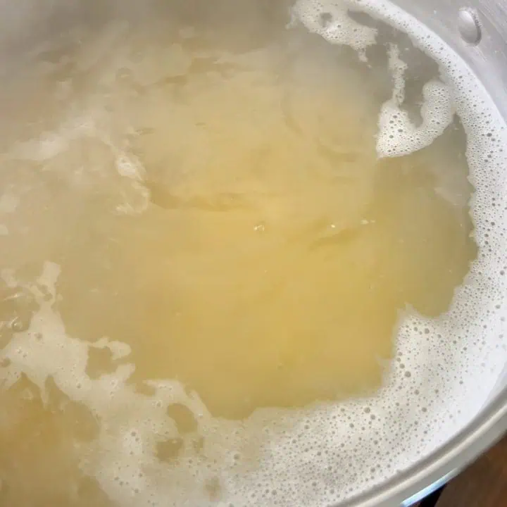 A pot filled with water boiling pasta with steam rising.