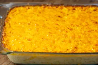 A casserole dish filled with baked mac and cheese with egg, showcasing a golden, bubbly texture on top.