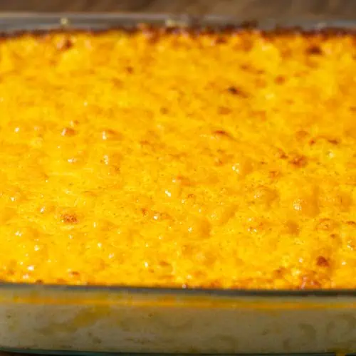 A casserole dish filled with baked mac and cheese with egg, showcasing a golden, bubbly texture on top.