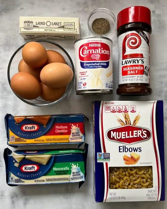 Ingredients for baked mac and cheese on white and gray background.