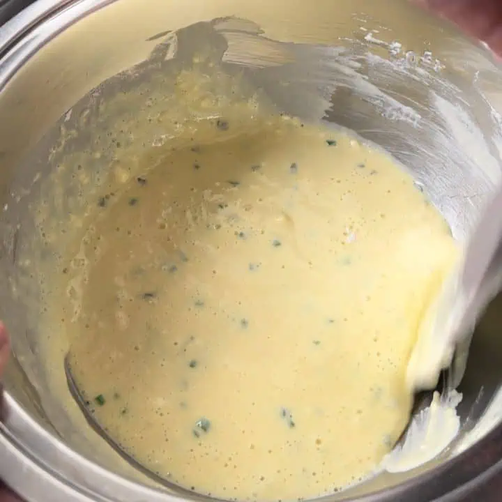 A mixing bowl filled with crepe batter with a rubber spatula on the side.