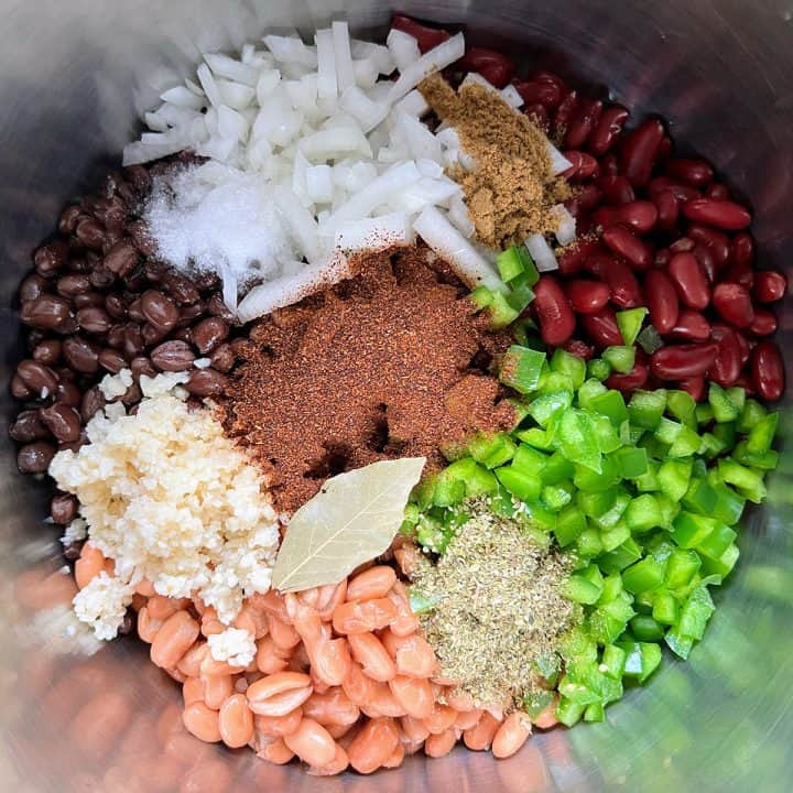 An Instant Pot filled with a mix of beans, onions, green bell peppers, and various spices, for chicken chili.