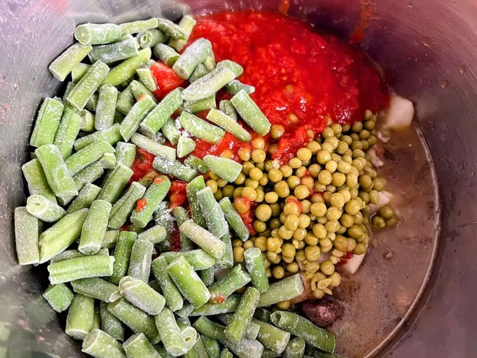 Frozen green beans and other vegetables for soup in a pot.