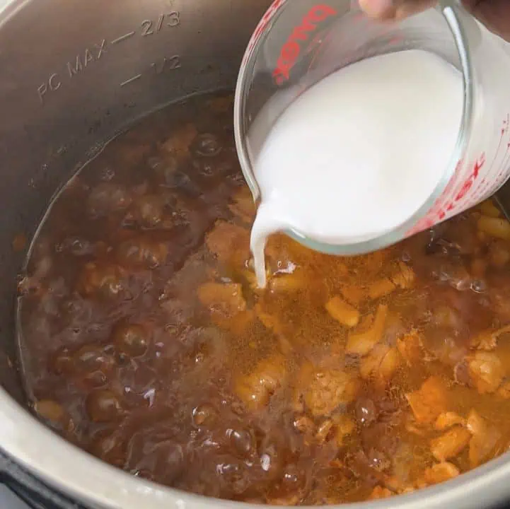 Pouring a cornstarch slurry into boiling baked beans.