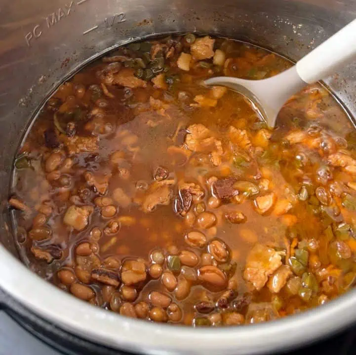 Stirring beans in a pressure cooker with a serving spoon